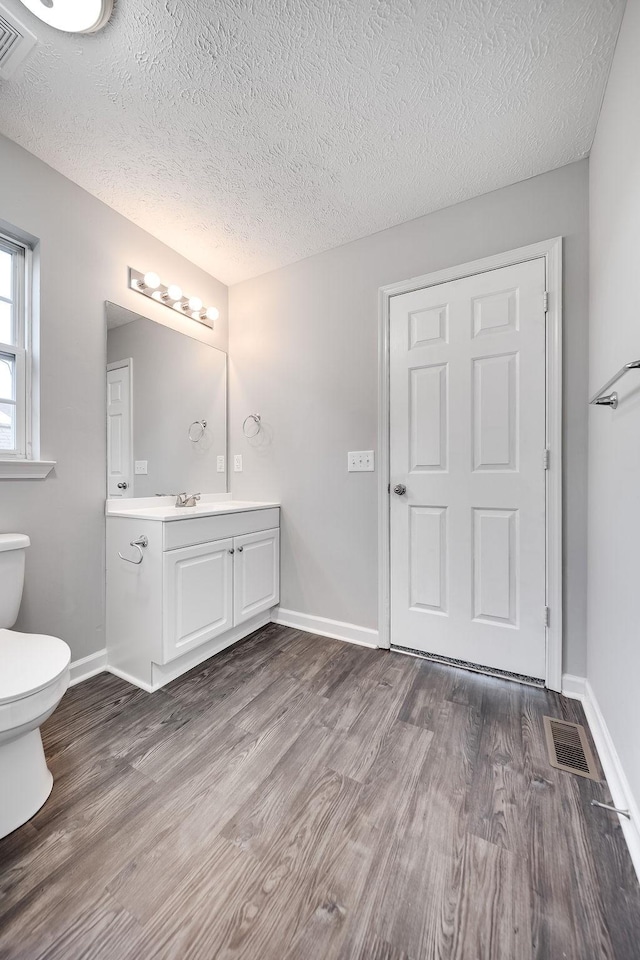 bathroom with hardwood / wood-style floors, toilet, vanity, and a textured ceiling