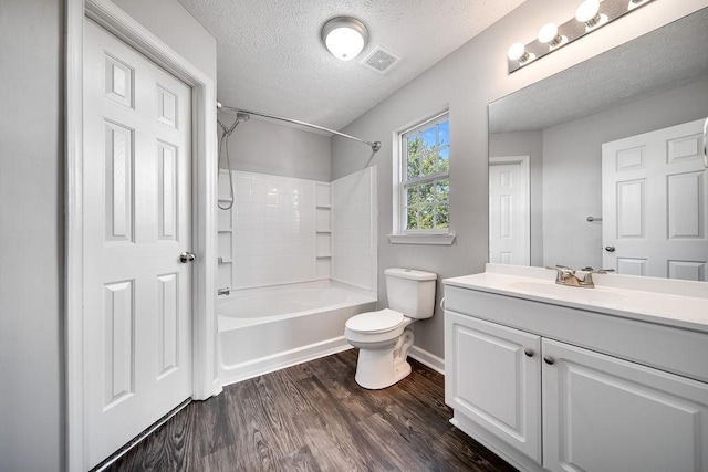 full bathroom featuring toilet, a textured ceiling, wood-type flooring, vanity, and washtub / shower combination