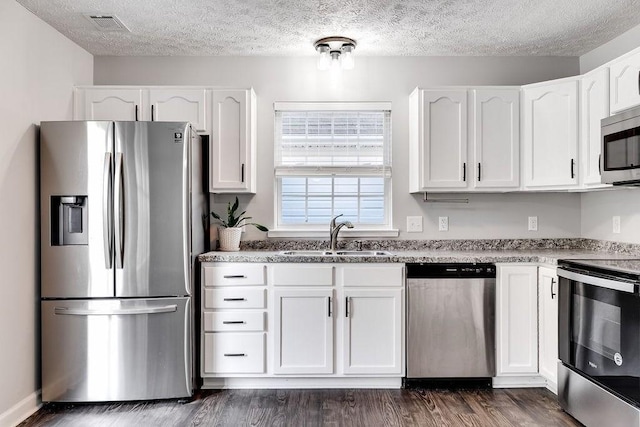 kitchen with white cabinets, a textured ceiling, appliances with stainless steel finishes, and sink