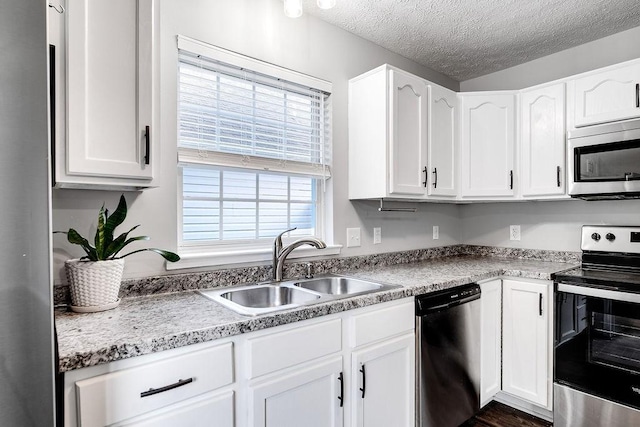 kitchen with white cabinets, appliances with stainless steel finishes, a textured ceiling, and sink