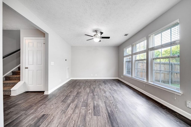 empty room with ceiling fan, dark wood-type flooring, and a textured ceiling