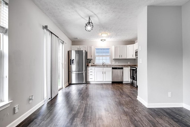 kitchen featuring appliances with stainless steel finishes, sink, white cabinetry, a textured ceiling, and dark hardwood / wood-style floors