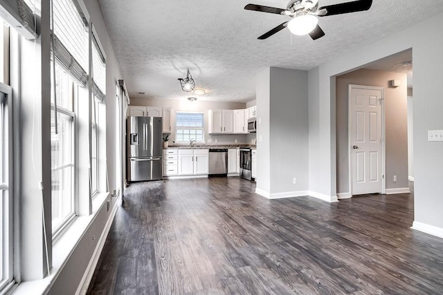 unfurnished living room featuring ceiling fan, sink, a textured ceiling, and dark hardwood / wood-style floors