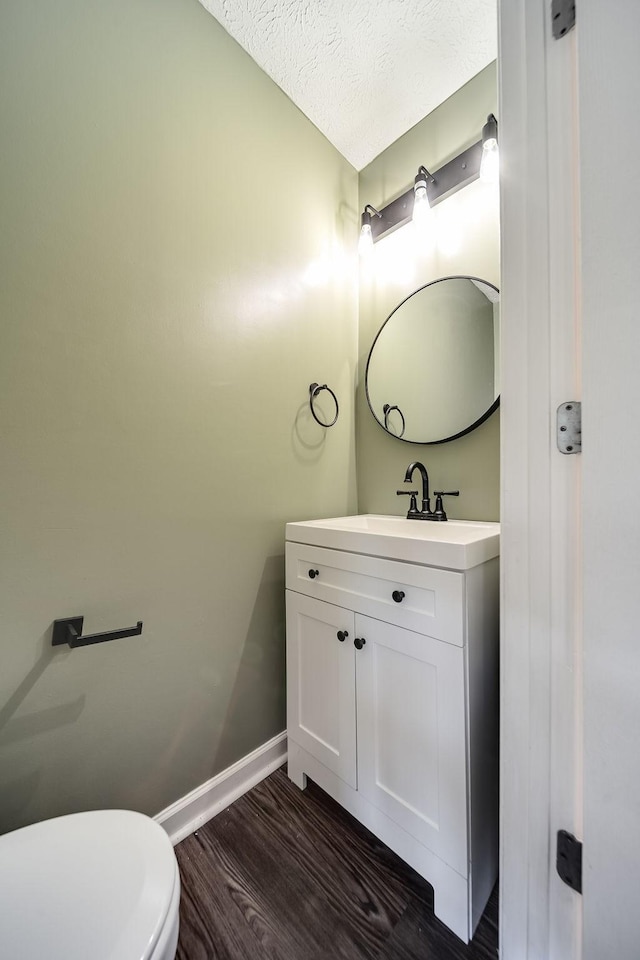 bathroom with wood-type flooring, a textured ceiling, toilet, and vanity