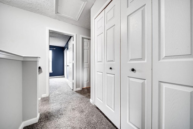 corridor featuring dark carpet and a textured ceiling