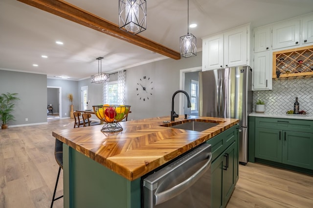 kitchen with sink, appliances with stainless steel finishes, a kitchen island with sink, white cabinetry, and beam ceiling