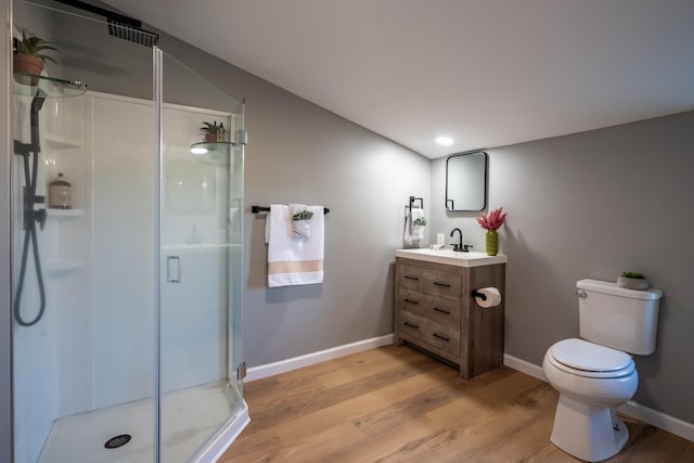 bathroom featuring vanity, hardwood / wood-style flooring, a shower with shower door, and toilet