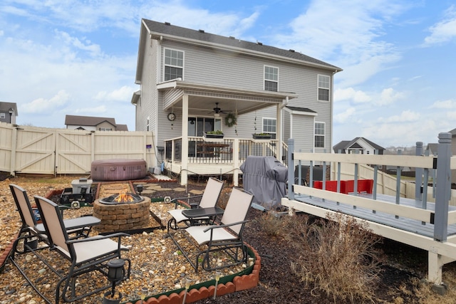 rear view of house with ceiling fan, a deck, and an outdoor fire pit