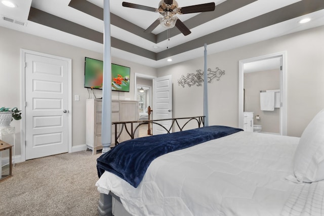 carpeted bedroom featuring ceiling fan, connected bathroom, and a tray ceiling