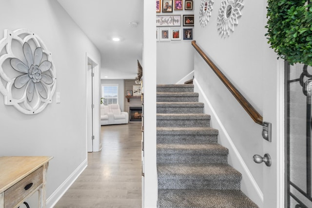 stairs with a fireplace and hardwood / wood-style flooring