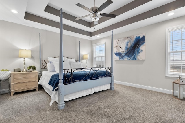 carpeted bedroom with ceiling fan and a raised ceiling