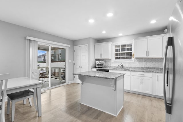 kitchen featuring white cabinets, a center island, light stone countertops, and stainless steel refrigerator with ice dispenser