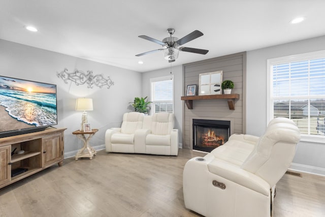 living room featuring light hardwood / wood-style floors, ceiling fan, and a fireplace