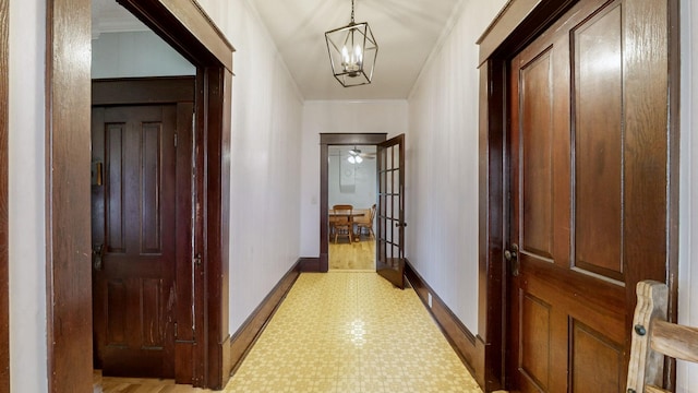 hall with light floors, baseboards, a chandelier, and ornamental molding