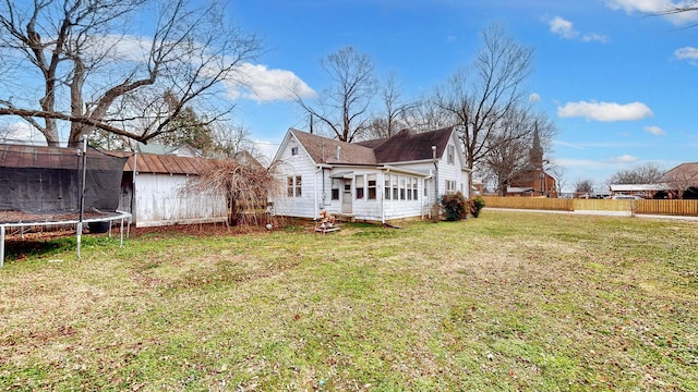 back of house with a trampoline and a yard