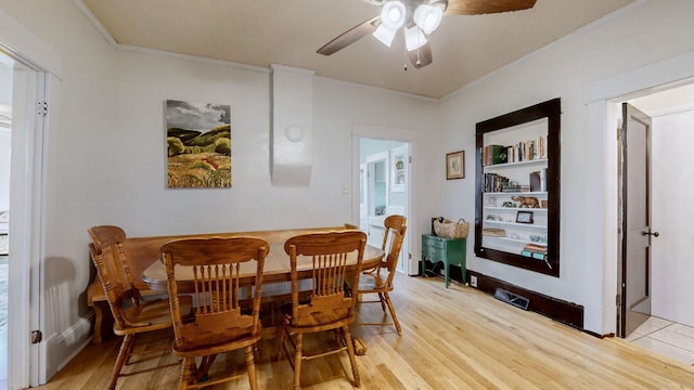 dining area with ceiling fan, built in shelves, ornamental molding, and light wood-type flooring