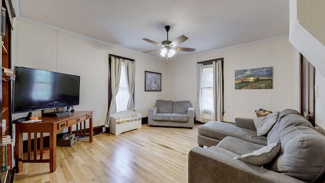 living room featuring ceiling fan, a textured ceiling, light hardwood / wood-style flooring, and ornamental molding