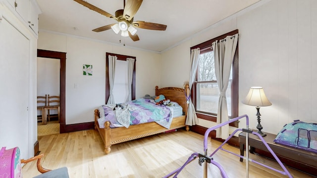 bedroom with ceiling fan, crown molding, baseboards, and wood finished floors