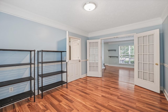 spare room with wood-type flooring, ornamental molding, a textured ceiling, and french doors