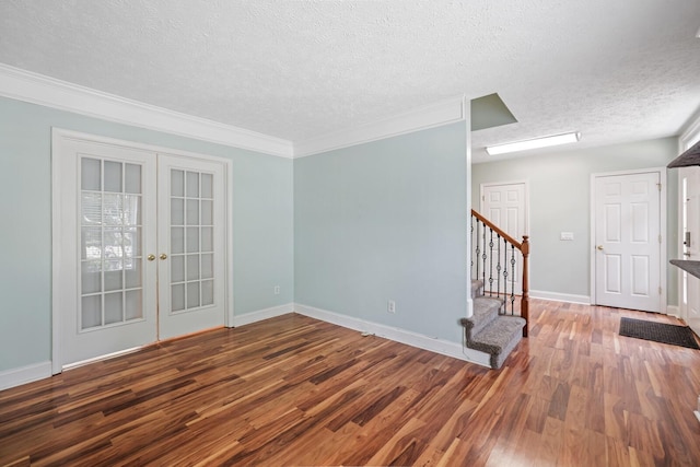 empty room with french doors, crown molding, dark hardwood / wood-style flooring, and a textured ceiling