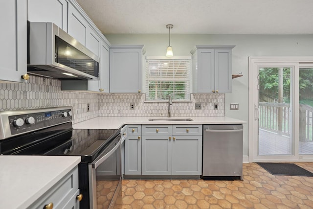 kitchen with sink, pendant lighting, gray cabinetry, and appliances with stainless steel finishes