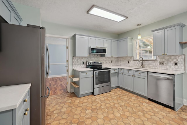 kitchen featuring stainless steel appliances, decorative backsplash, sink, hanging light fixtures, and gray cabinets