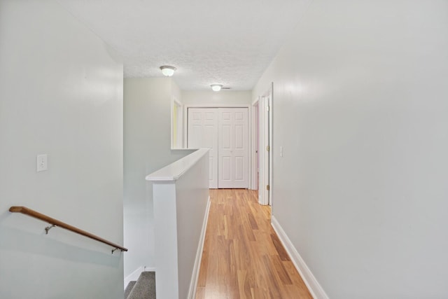 corridor featuring light wood-type flooring and a textured ceiling