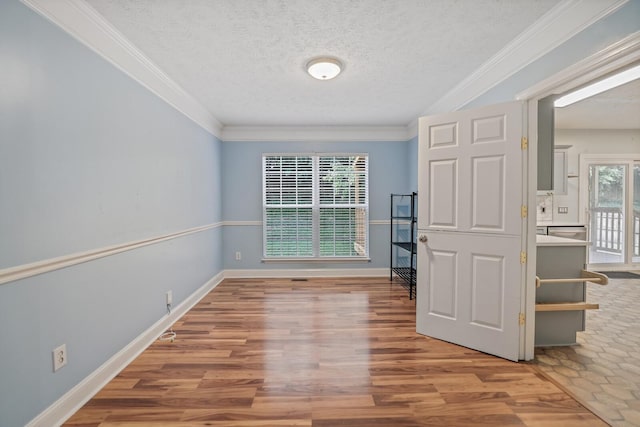 empty room featuring hardwood / wood-style floors, a healthy amount of sunlight, a textured ceiling, and ornamental molding