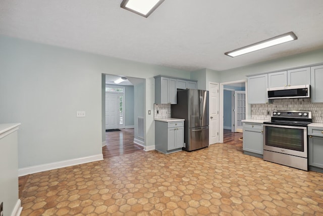 kitchen featuring decorative backsplash, gray cabinetry, and appliances with stainless steel finishes