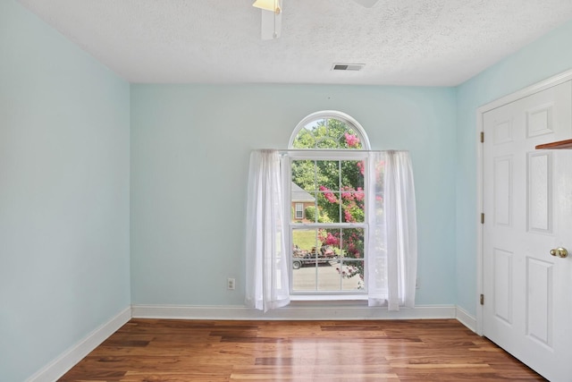 unfurnished room featuring ceiling fan, hardwood / wood-style floors, and a textured ceiling