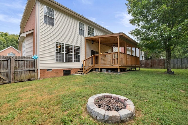 rear view of property with an outdoor fire pit, a wooden deck, and a yard