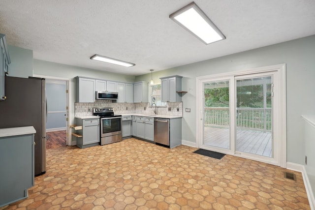 kitchen with decorative light fixtures, sink, gray cabinetry, decorative backsplash, and stainless steel appliances