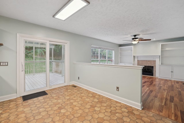 interior space with a tile fireplace, a textured ceiling, and ceiling fan