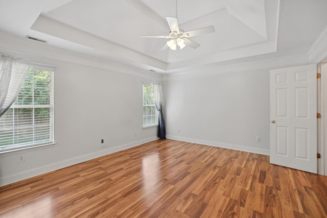 unfurnished room with ornamental molding, ceiling fan, a raised ceiling, and light hardwood / wood-style flooring