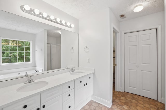 bathroom with independent shower and bath, a textured ceiling, and vanity