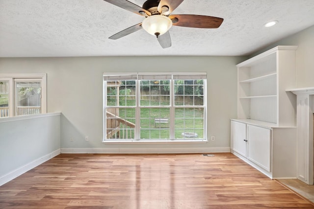 empty room featuring ceiling fan, a textured ceiling, and light hardwood / wood-style flooring