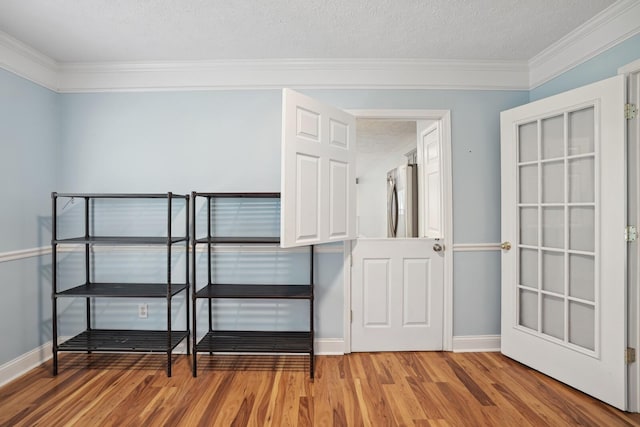 interior space featuring crown molding, hardwood / wood-style flooring, a textured ceiling, and stainless steel refrigerator