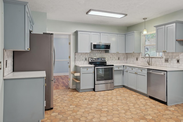 kitchen with appliances with stainless steel finishes, a textured ceiling, hanging light fixtures, gray cabinetry, and sink