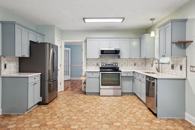 kitchen featuring appliances with stainless steel finishes, decorative backsplash, gray cabinetry, sink, and decorative light fixtures