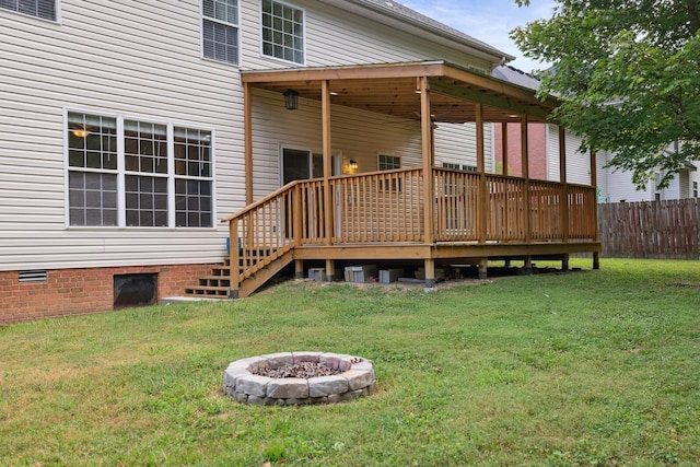 back of house featuring an outdoor fire pit, a lawn, and a wooden deck