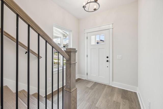 entryway with plenty of natural light, a notable chandelier, and light wood-type flooring