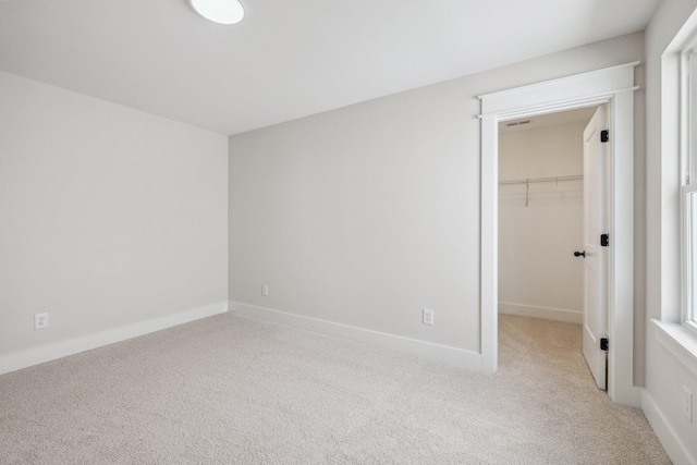 unfurnished bedroom featuring a walk in closet, light carpet, and a closet