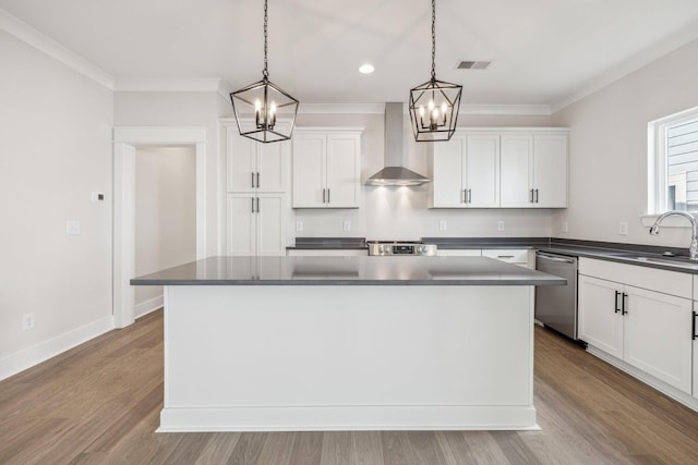 kitchen with hanging light fixtures, sink, wall chimney range hood, a kitchen island, and stainless steel appliances