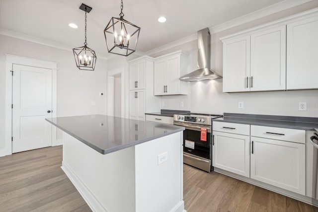 kitchen featuring decorative light fixtures, white cabinets, wall chimney range hood, ornamental molding, and stainless steel electric range