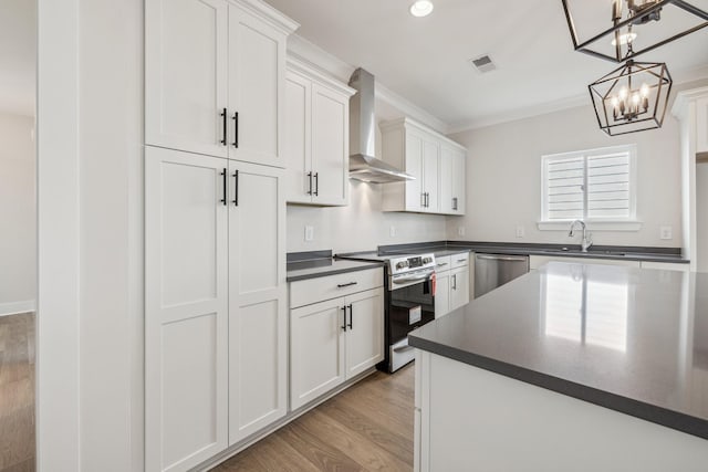 kitchen with wall chimney exhaust hood, decorative light fixtures, white cabinets, and appliances with stainless steel finishes