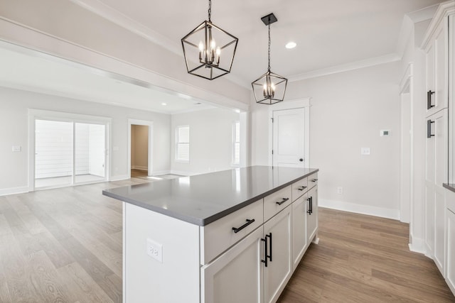 kitchen with white cabinets, pendant lighting, light wood-type flooring, and a center island