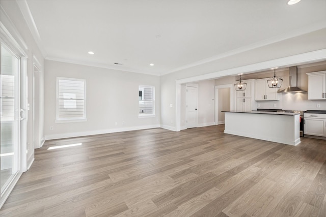 unfurnished living room featuring a healthy amount of sunlight, ornamental molding, and light hardwood / wood-style floors