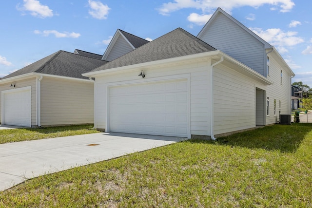 view of side of home featuring a garage, a lawn, and central AC