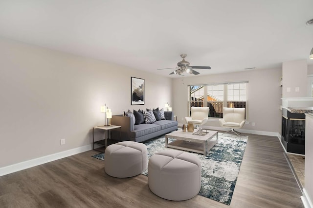 living room with ceiling fan, a multi sided fireplace, and dark hardwood / wood-style floors