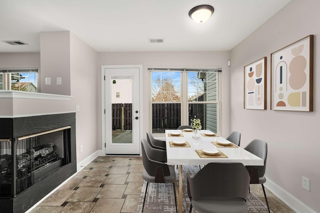 dining room with a multi sided fireplace and plenty of natural light